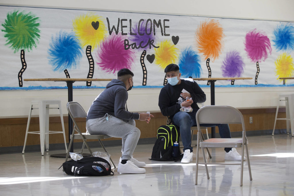 Angel Bermudez and his brother, Manuel, chat over lunch during the first day of in-person school at Everett High on Monday. (Andy Bronson / The Herald)
