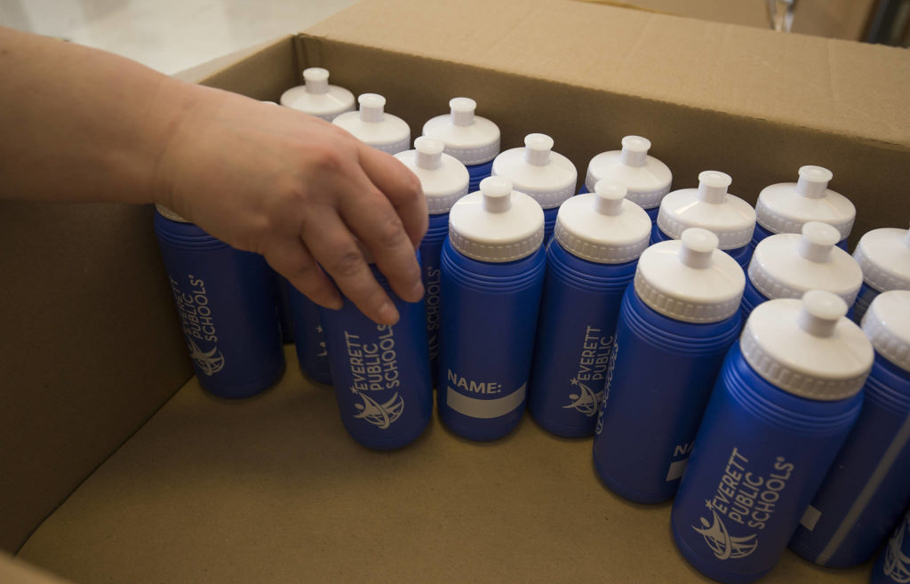 Students grab water bottles — fountains are closed — during the first day of in-person school for Everett High on Monday. (Andy Bronson / The Herald) 
