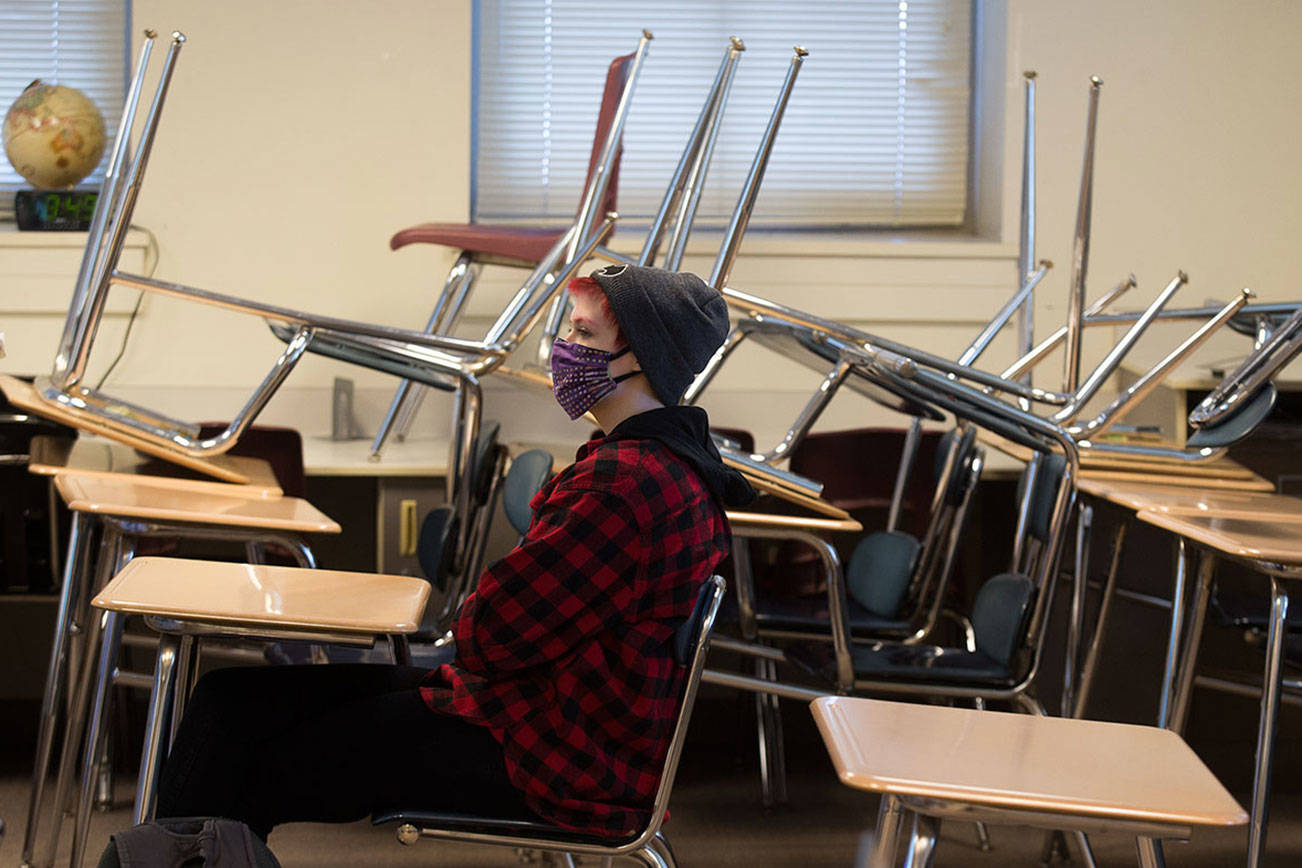 With desks stacked away to provide social distance spacing, tenth grader Zendon Bugge attends a World History class during the first day of school for Everett High students on Monday, April 19, 2021 in Everett, Washington.  (Andy Bronson / The Herald)