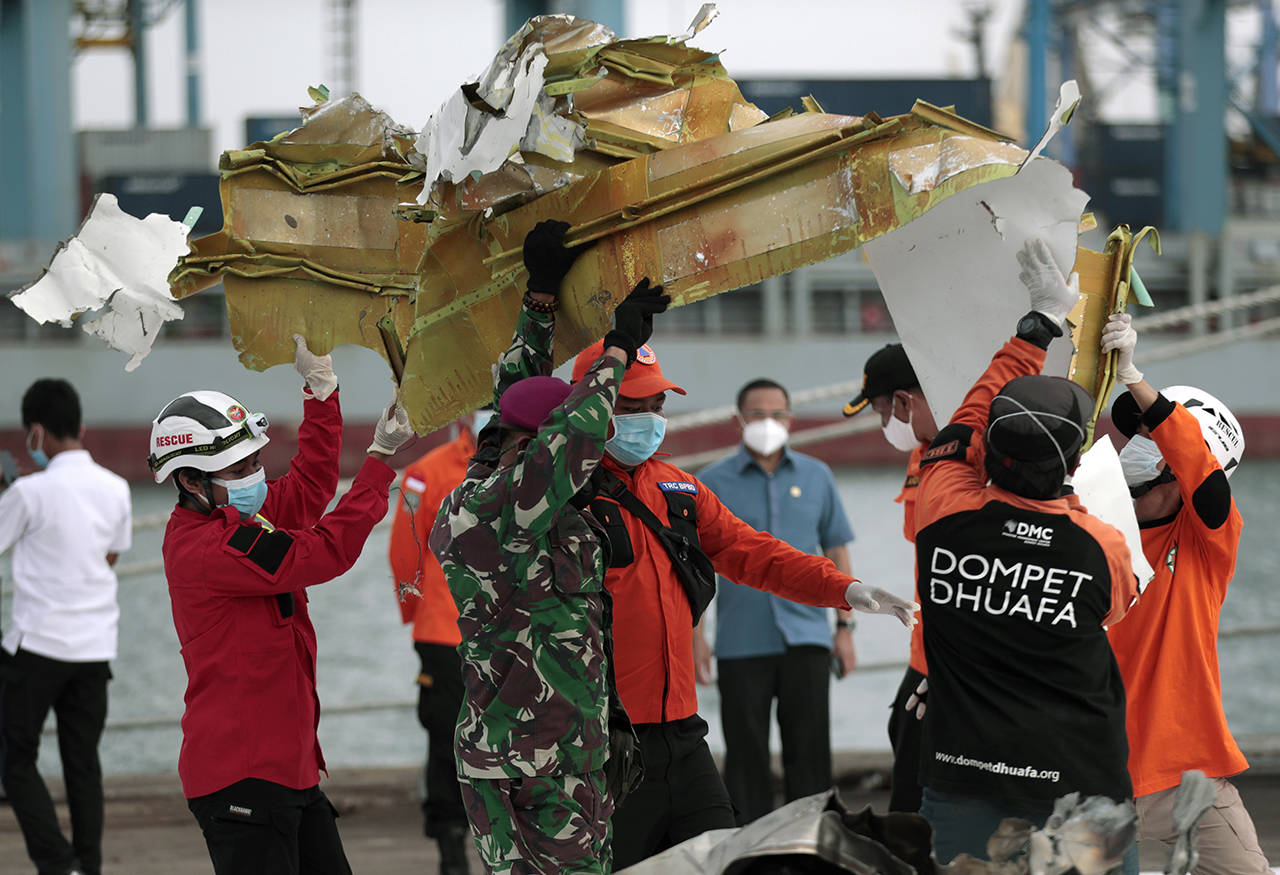 Rescuers carry a part of aircraft recovered from Java Sea where a Sriwijaya Air passenger jet crashed, at Tanjung Priok Port in Jakarta, Indonesia, on Jan. 11. (AP Photo/Dita Alangkara, file)