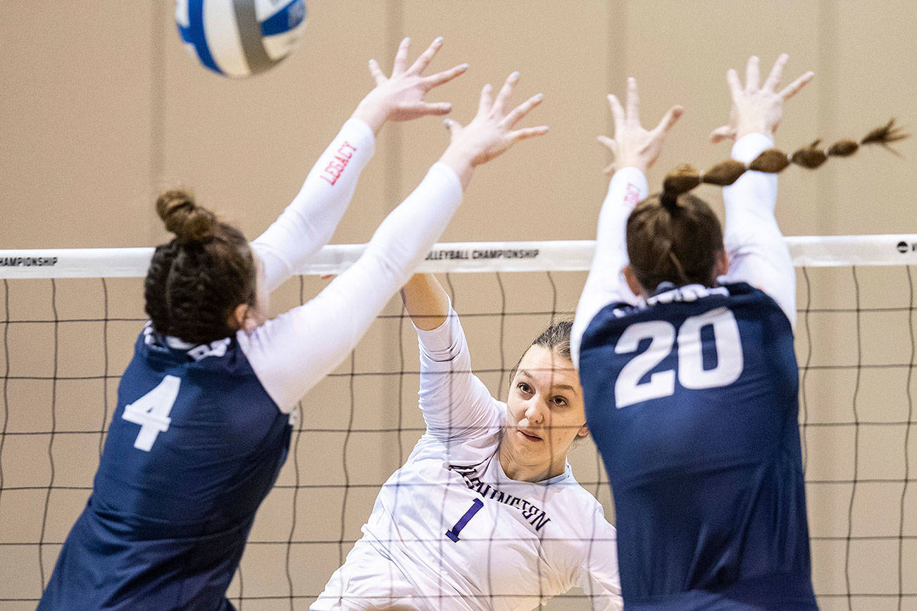 Washington's Lauren Sanders, center, spikes the ball against Dayton's Lexie Almodovar, left, and Lindsey Winner, right, in the third set during an NCAA volleyball tournament in Omaha, Neb., Thursday, April 15, 2021. (Chris Machian/Omaha World-Herald via AP)