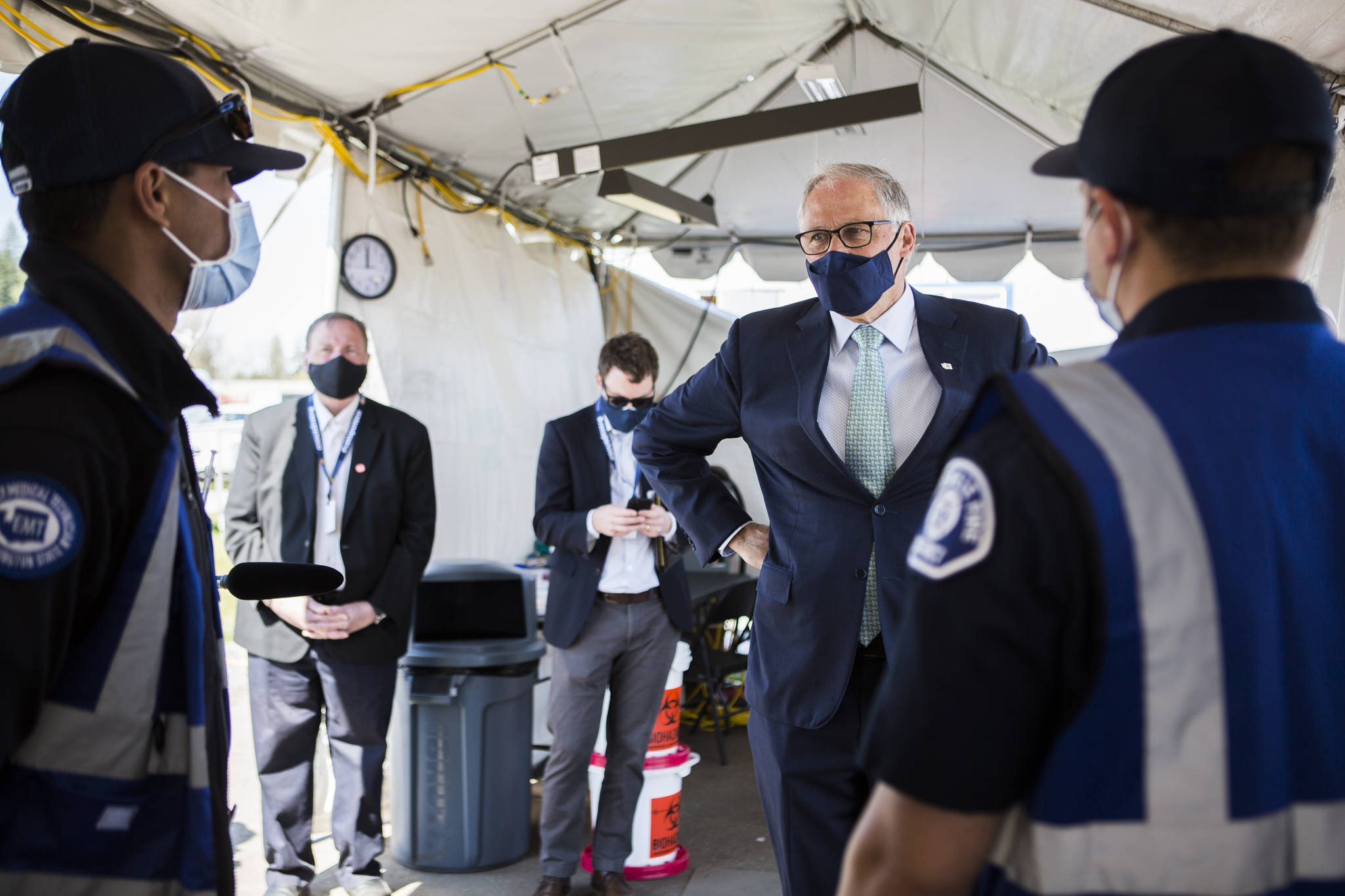 Gov. Jay Inslee speaks with Marysville firefighters Luis Cruz (left) and Chris Brunett about being vaccinators at a COVID-19 vaccination site on Tuesday in Arlington. (Olivia Vanni / The Herald)