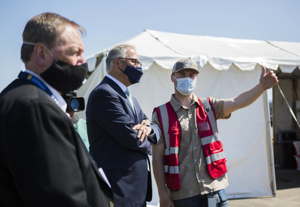 Gov. Jay Inslee speaks with pod manager Peyton Plucker at the mass vaccination site at Arlington Municipal Airport on Tuesday. (Olivia Vanni / The Herald)

