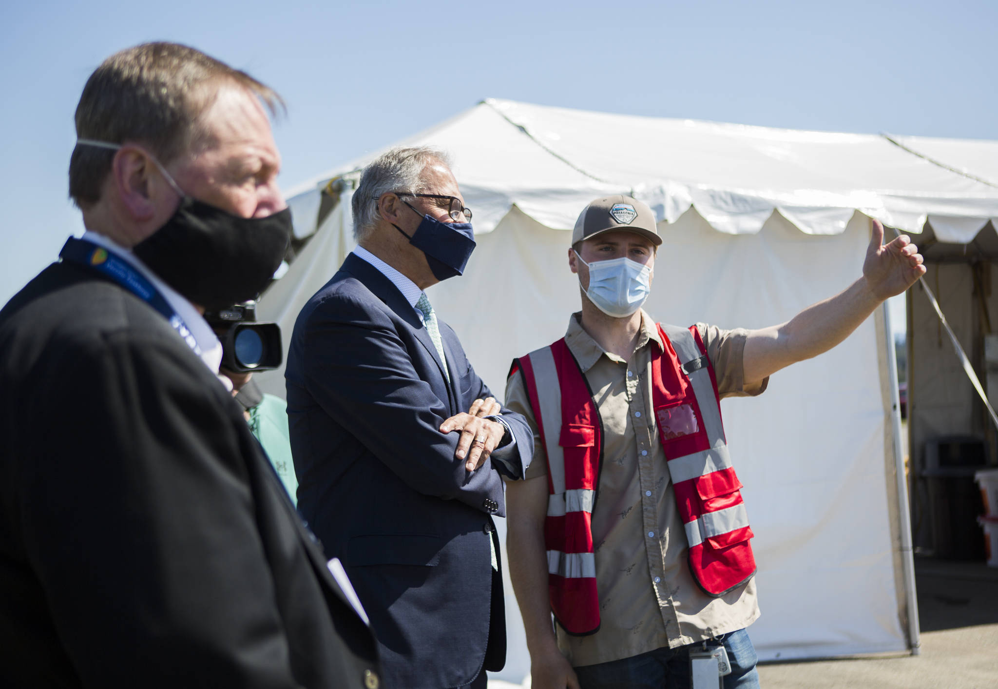 Gov. Jay Inslee speaks with pod manager Peyton Plucker at the mass vaccination site at Arlington Municipal Airport on Tuesday. (Olivia Vanni / The Herald)