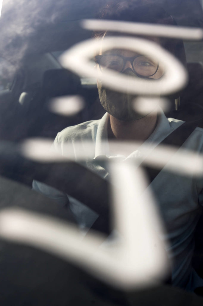 A time is written on the windshield of Herald reporter Joey Thompson’s car to help volunteers monitor the wait time after he got his first shot of the Pfizer COVID-19 vaccine at the Ash Way Park & Ride site Wednesday in Lynnwood. (Andy Bronson / The Herald)
