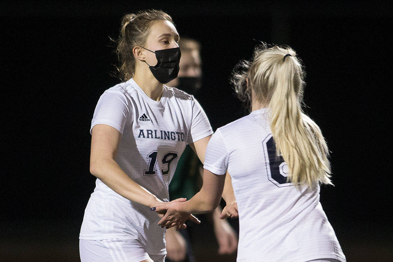 Arlington's Jersey Heiss, left, gets a hand from Ellie Rork as the Eagles lead 2-1 against Marysville Getchell in the first half of first girls' soccer match of their season on Wednesday, March 3, 2021 in Marysville, Washington.  (Andy Bronson / The Herald)