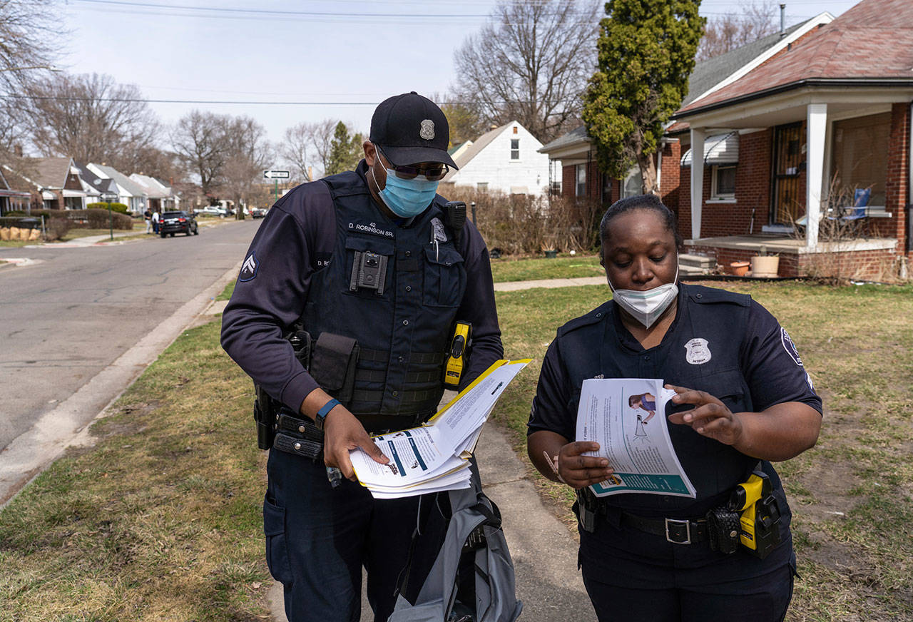 Detroit Police Department Neighborhood Officer Marcia Williams (right) organizes papers to deliver door-to-door with Neighborhood Officer Dan Robinson as they distribute gun safety information and gun locks to residents along Fenelon Street on Detroit’s east side on March 25. Residents said they feel safer in their neighborhoods with police presence and the work of the department’s neighborhood officers. (Ryan Garza / Detroit Free Press)