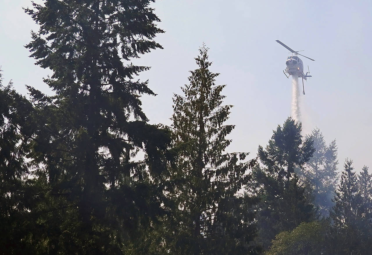 In this Sept. 9, 2020 photo, a helicopter makes a water drop on a hotspot of a wildfire burning in Bonney Lake. (AP Photo/Ted S. Warren, Pool, File)