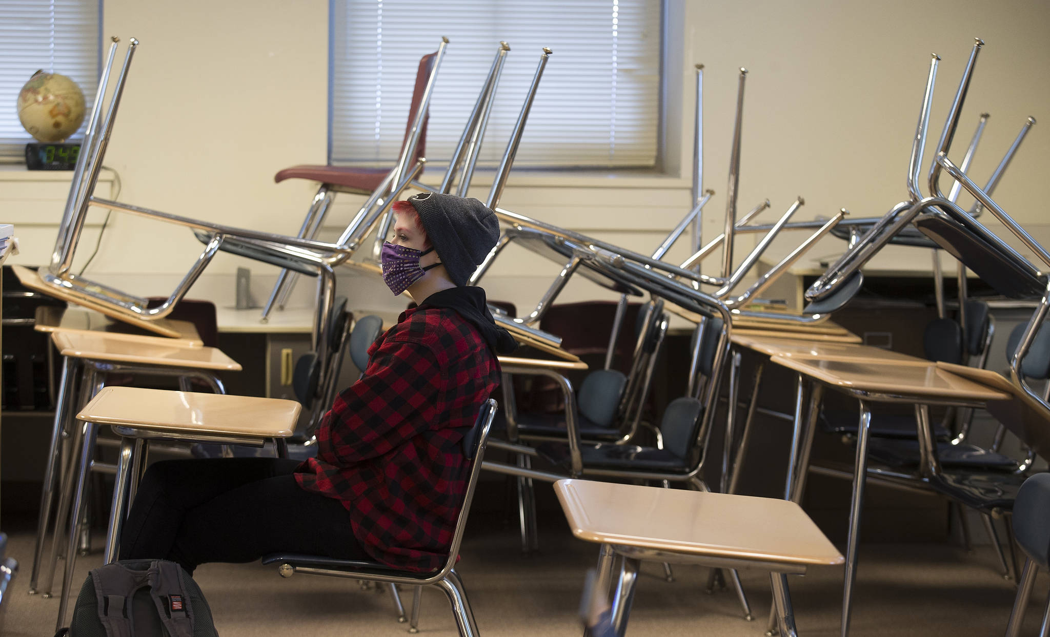 With desks stacked away to provide social distance spacing, tenth grader Zendon Bugge attends a World History class during the first day of school for Everett High students on Monday, April 19, 2021 in Everett, Washington.  (Andy Bronson / The Herald)