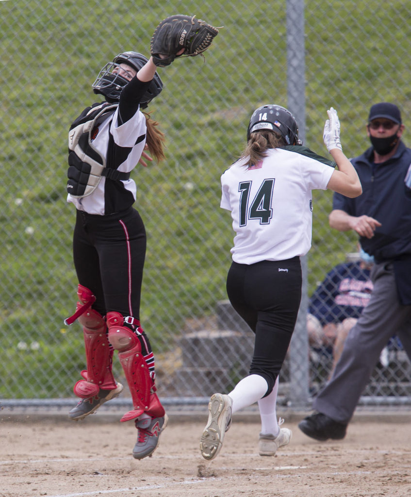 Jackson’s Macie Dean (right) crosses home plate for a run as Marysville Pilchuck’s Riley Perrine leaps leaps for the ball during a game on April 28, 2021, in Mill Creek. Jackson beat Marysville Pilchuck 6-0. (Andy Bronson / The Herald)
