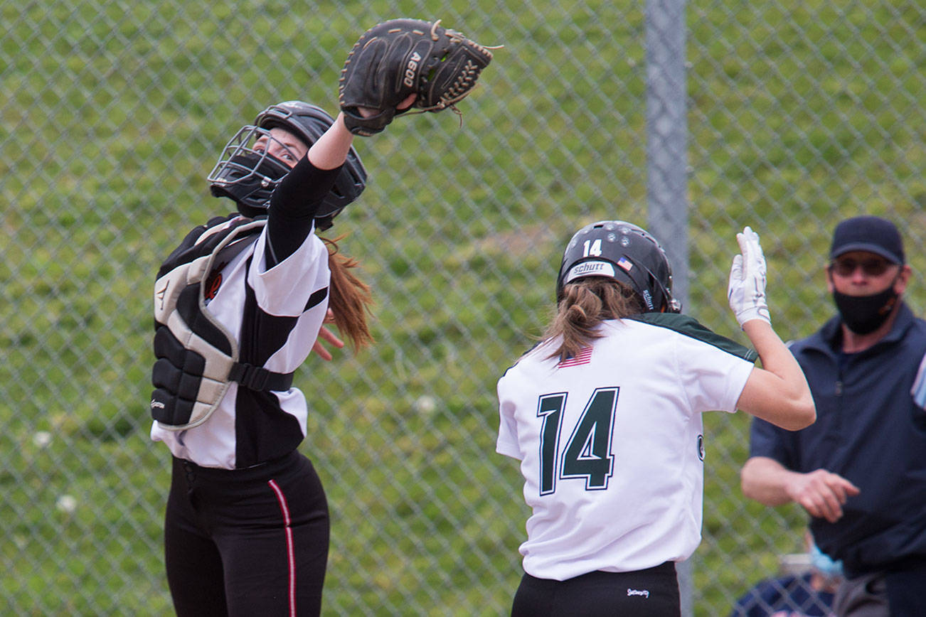 Marysville Pilchuck's Riley Perrine leaps as Jackson's Macie Dean crosses home plate for a run as undefeated Jackson beat Marysville Pilchuck 6-0 in a fastpitch game on Wednesday, April 28, 2021 in Mill Creek, Washington.  (Andy Bronson / The Herald)