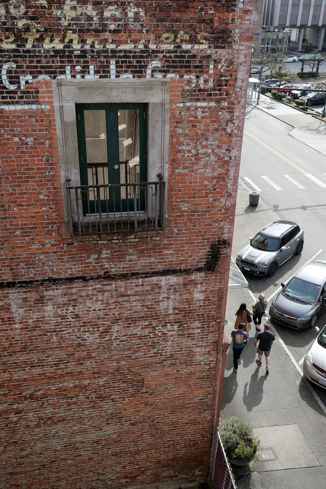 Pedestrians walk beside a brick building on Wetmore Avenue in Everett. Old buildings constructed before 1945, with unreinforced masonry, are vulnerable to seismic waves. The exterior could break away and plummet into the street. (Andy Bronson / The Herald)