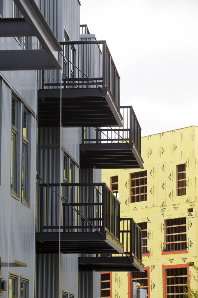 The Waterfront Place, which has 135 apartments, is being shown and leased at its Port of Everett location. Residents of the north building (left) could begin moving in by May 15. The south building (right), which burned down in 2020, is being rebuilt and will open next year with another 131 apartments. (Andy Bronson / The Herald)
