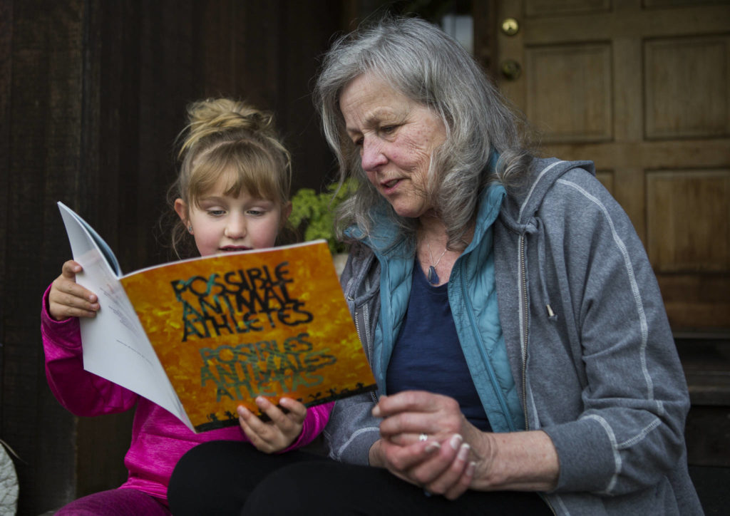 Henri Wilson, who helped create a children’s book with teens in Snohomish County Juvenile Court’s detention alternatives and diversion programs, flips through “Possible Animal Athletes” with her granddaughter, Alexa Estes, 5, on April 27 in Everett. (Olivia Vanni / The Herald)
