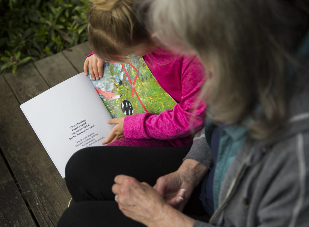 Alexa Estes, 5, talks to her grandmother Henri Wilson about which illustrations are her favorites in the “Possible Animal Athletes” book. (Olivia Vanni / The Herald)
