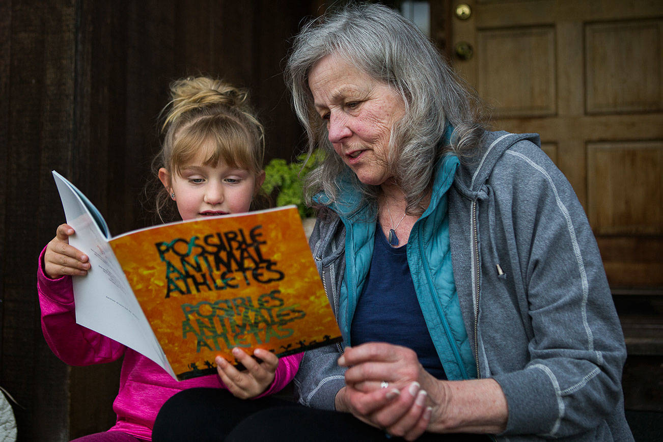 Henri Wilson, who helped create a children's book with teens in Snohomish County Juvenile Court's detention alternatives and diversion programs, flips through "Possible Animal Athletes" with her granddaughter, Alexa Estes, 5, on Tuesday, April 27, 2021 in Everett, Wash. (Olivia Vanni / The Herald)