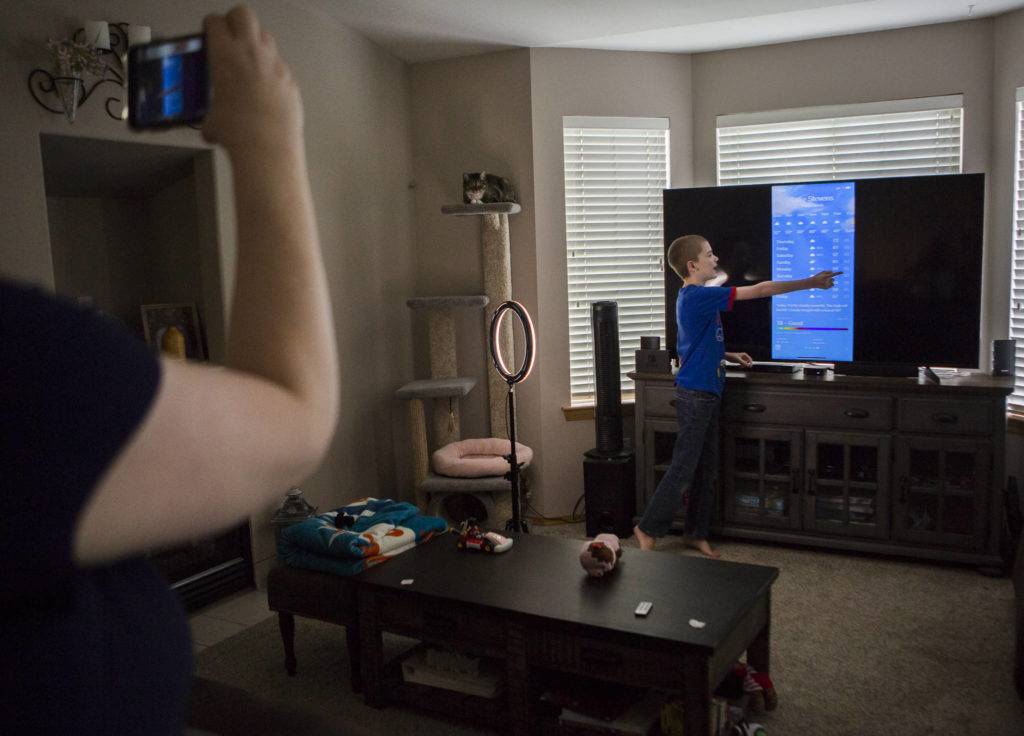 Tonya Stowell records her son David during his daily local weather report. (Olivia Vanni / The Herald)
