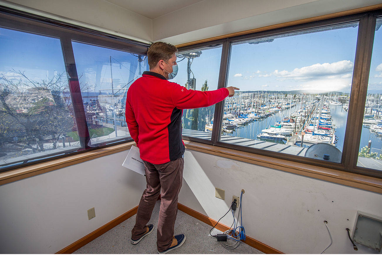 From the third floor crow's nest of its new building in the port's South Marina, Everett Yacht Club Commodore John Seger points out what will be the club's dock on Tuesday, May 4, 2021 in Everett, Washington.  (Andy Bronson / The Herald)