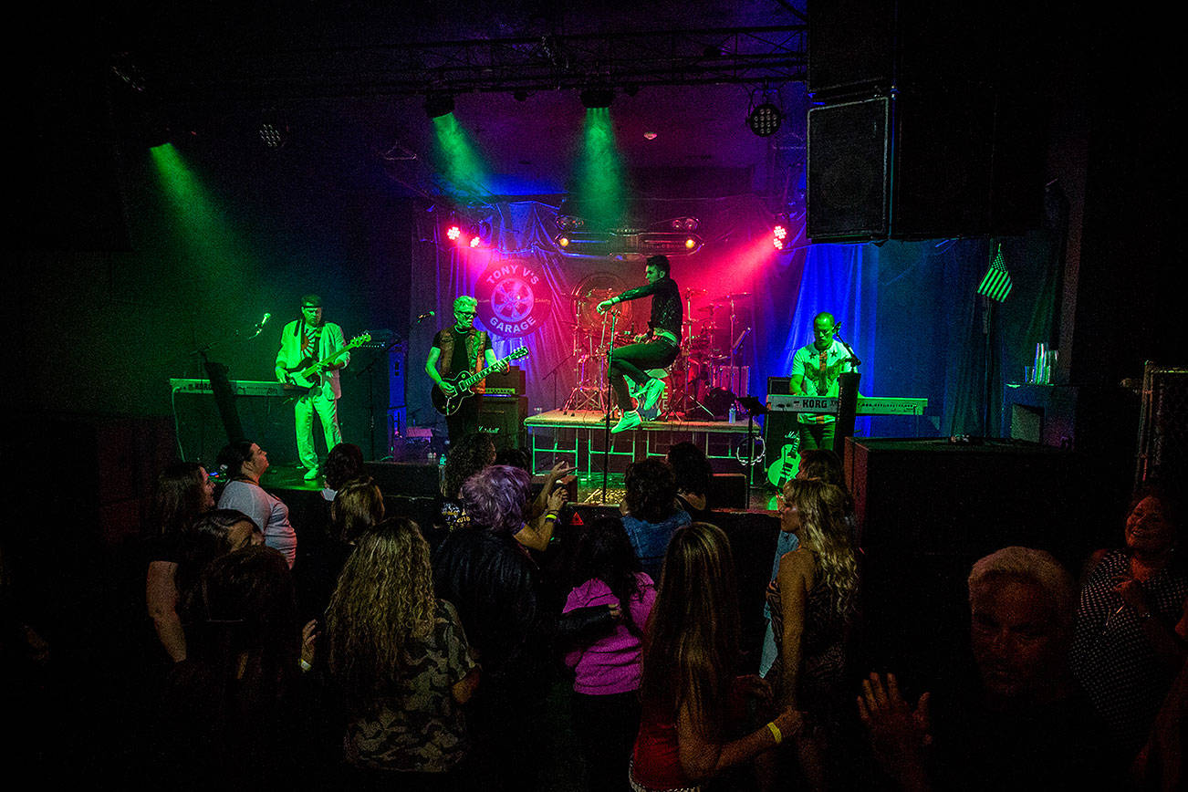 Michael Henrichsen, center, leaps across the stage as people dance during Nite Wave's show at Tony V's Garage on Saturday, June 8, 2019 in Everett, Wash. (Olivia Vanni / The Herald)