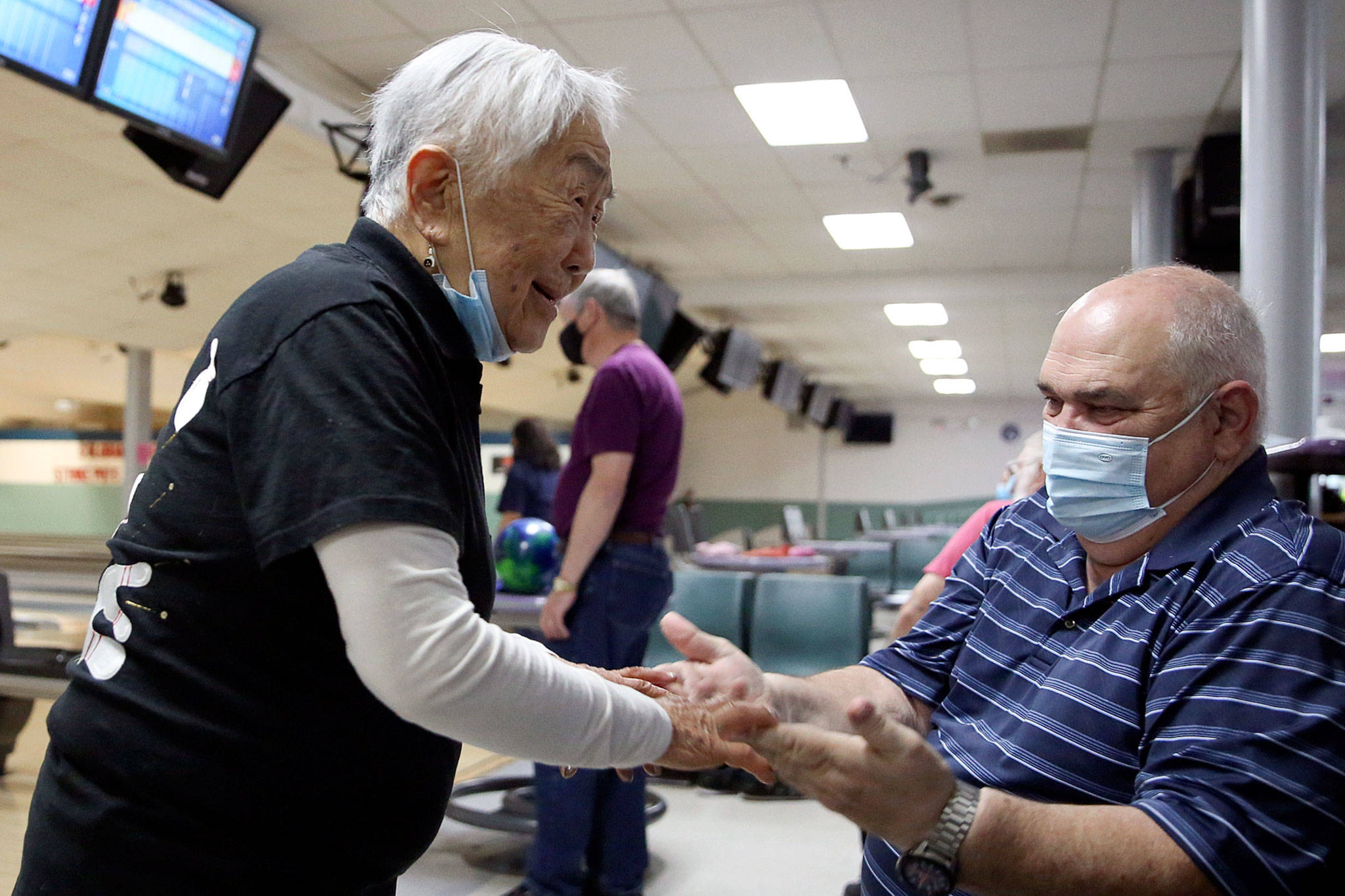 Mae Tomita (left) celebrates with Richard Steele after picking up a spare in the first frame Wednesday afternoon at Strawberry Lanes in Marysville. (Kevin Clark / The Herald)