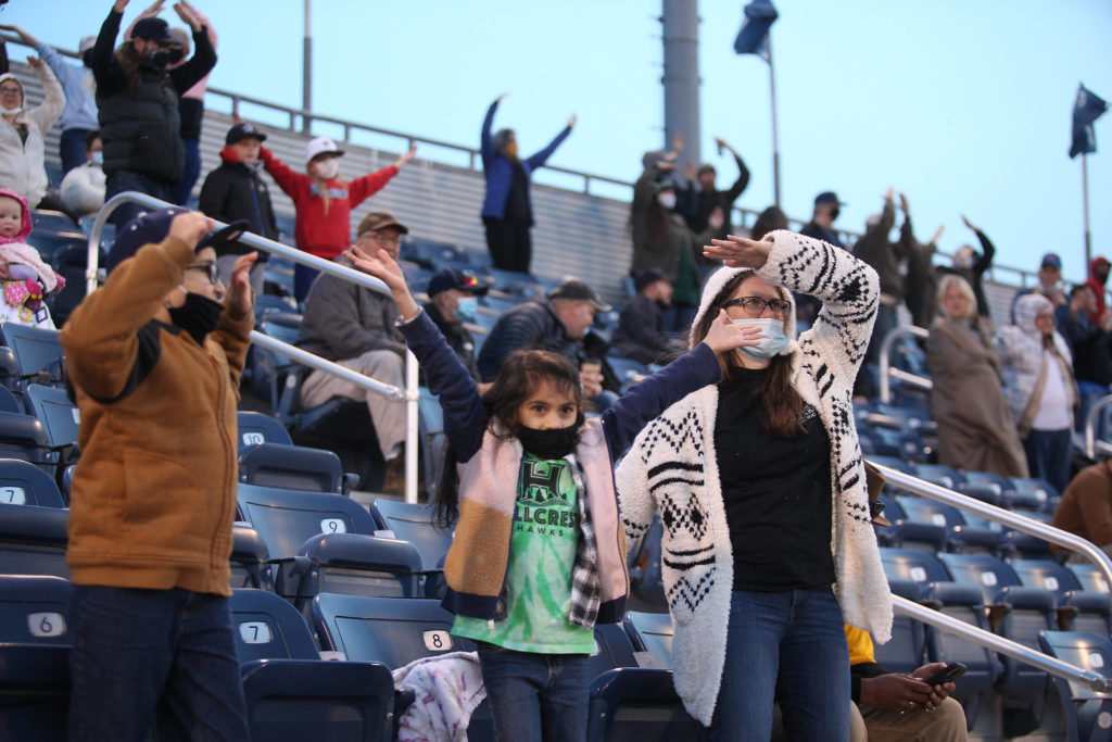 Fans dance to the song “YMCA” as the Everett Aquasox beat the Tri-City Dust Devils in a home opening game at Funko Field on Tuesday, May 11, 2021 in Everett, Washington. (Andy Bronson / The Herald)
