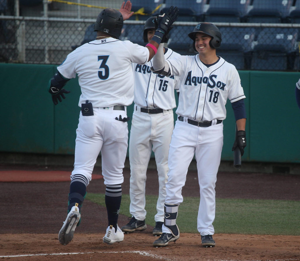 The AquaSox’s Julio Rodriguez gets a high five from Austin Shenton as he crosses home plate after hitting a two-run home run during a game against the Dust Devils on May 11, 2021, at Funko Field in Everett. (Andy Bronson / The Herald)
