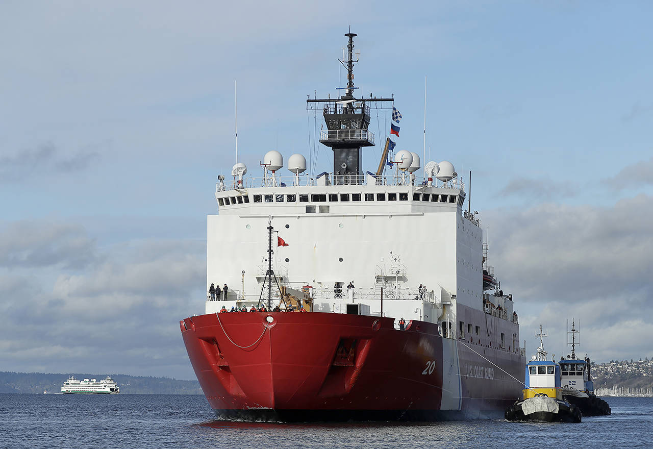 In this 2018 photo, tugboats help the U.S. Coast Guard Cutter Healy icebreaker into her homeport of Seattle, as a Washington state ferry passes in the background. (AP Photo/Ted S. Warre, File)