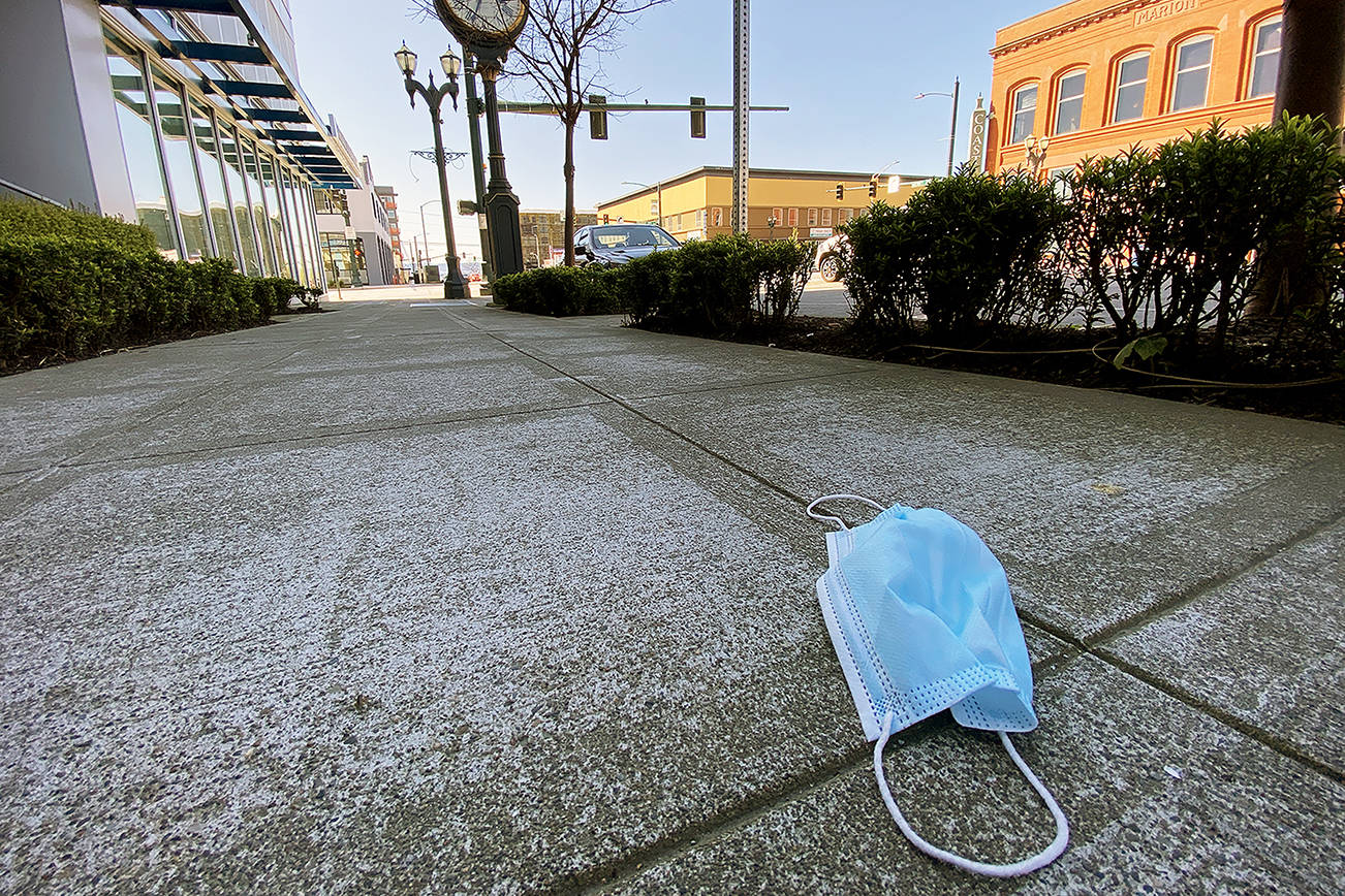 An abandoned face mask rests on the sidewalk along Hewitt Avenue in downtown Everett on April 15. (Sue Misao / The Herald)
