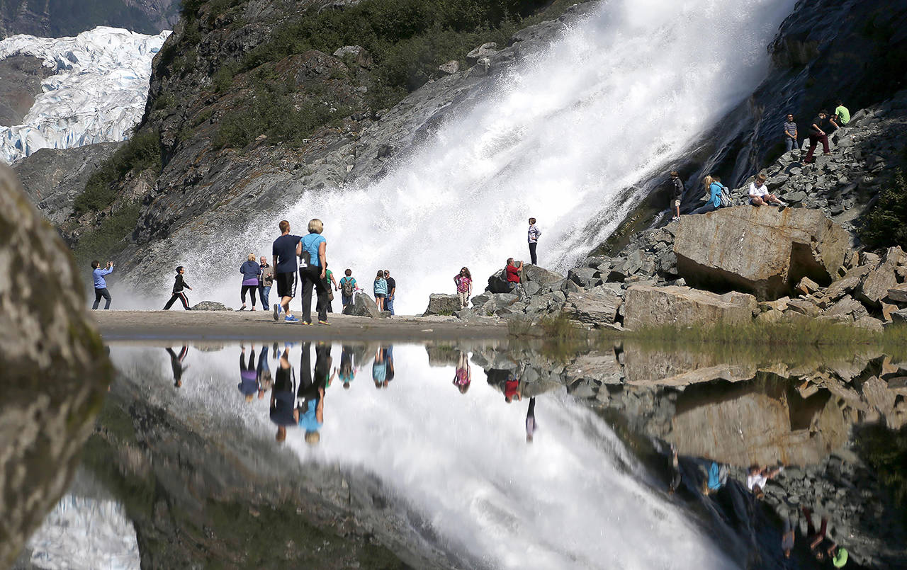 Tourists visiting the Mendenhall Glacier in the Tongass National Forest are reflected in a pool of water as they make their way to Nugget Falls in Juneau, Alaska, in late July, 2013. The U.S. Forest Service announced plans in 2020, to lift restrictions on road building and logging in Tongass National Forest, a largely pristine rainforest in southeast Alaska that provides habitat for wolves, bears and salmon. (Charles Rex Arbogast / Associated Press file photo)