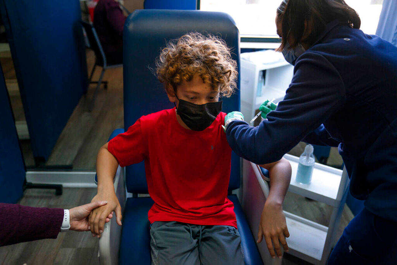 Max Cuevas, 12, holds his mother’s hand as he receives the Pfizer covid-19 vaccine from nurse practitioner Nicole Noche at Families Together of Orange County in Tustin, Calif., May 13. The state began vaccinating children ages 12 to 15 Thursday. (Jae C. Hong / Associated Press)