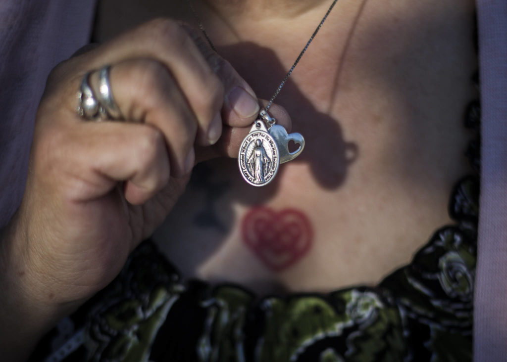 Two pendants, one of the Mother Mary and another of a heart with a heart-shaped hole, are worn by Beverly Bowers. (Olivia Vanni / The Herald) 
