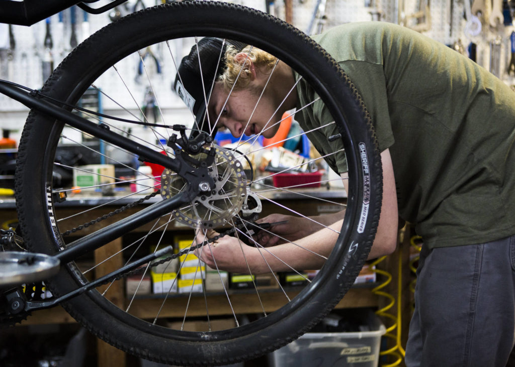 Gavin Buchanan works on a shifter cable for a customer Friday at Tim’s Bike Shop in Everett. Parts are getting harder to come by as manufacturers struggle to meet demand amid the COVID-19 pandemic. (Olivia Vanni / The Herald)
