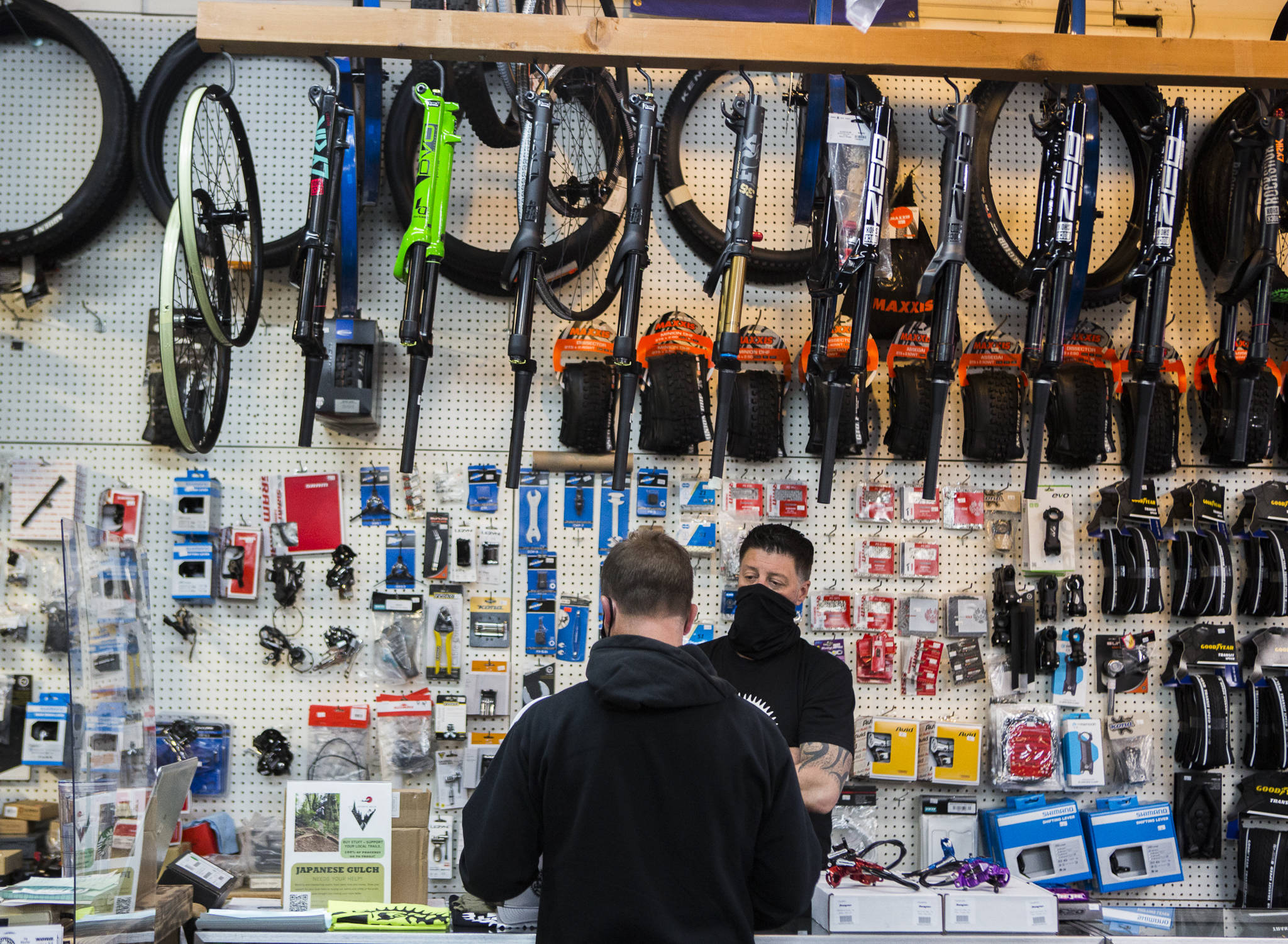 Jay Hiester, owner of Tim’s Bike Shop, helps a customer pick out a rear tire Friday in Everett. (Olivia Vanni / The Herald)