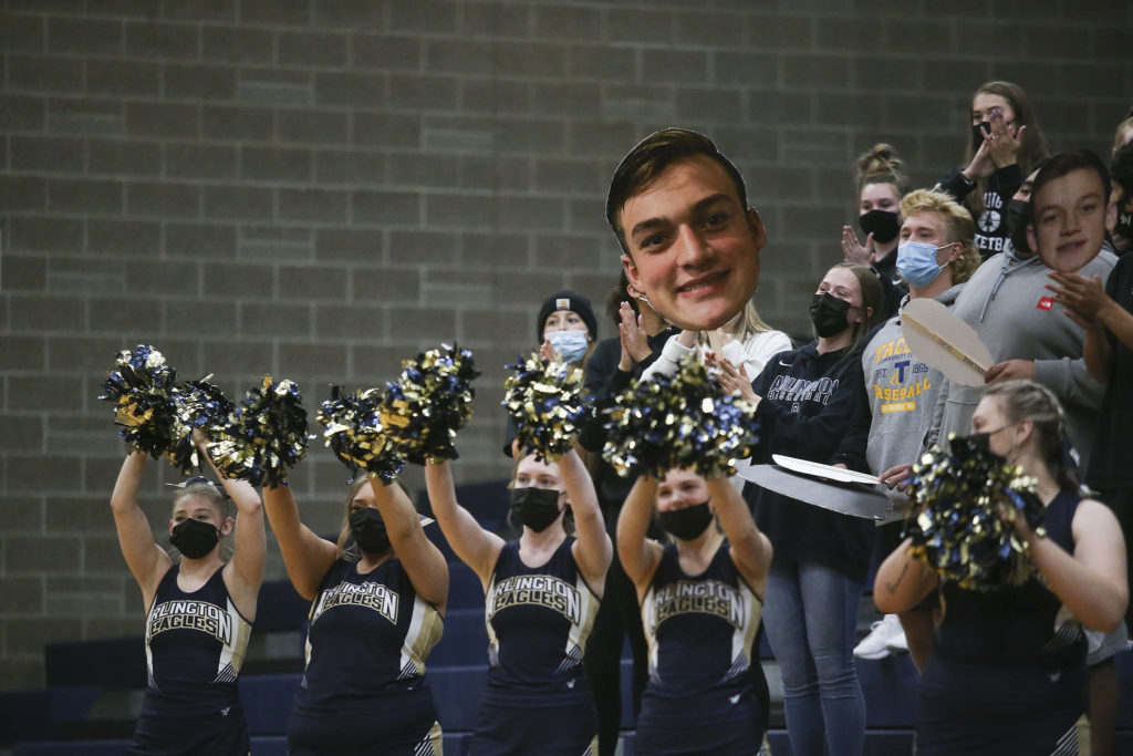 Arlington fans hold up a player’s photo as they cheer during a game against Lakewood on May 19, 2021, in Arlington. (Andy Bronson / The Herald)
