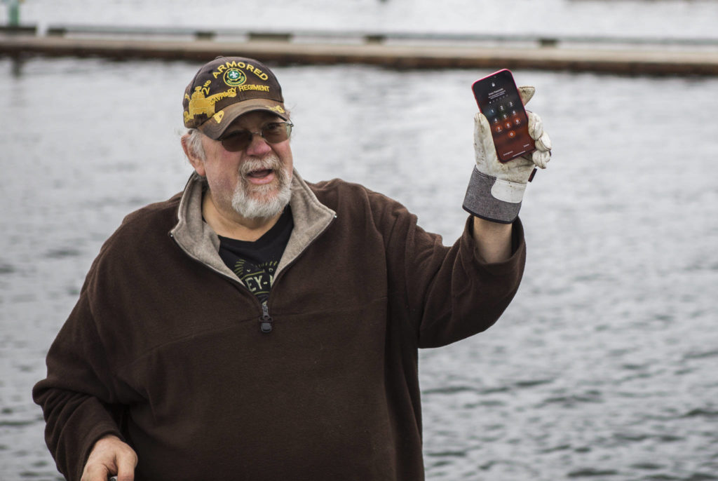 David Hoeft reacts to an iPhone found underwater after powering it on again May 23 in Lake Stevens. (Olivia Vanni / The Herald)
