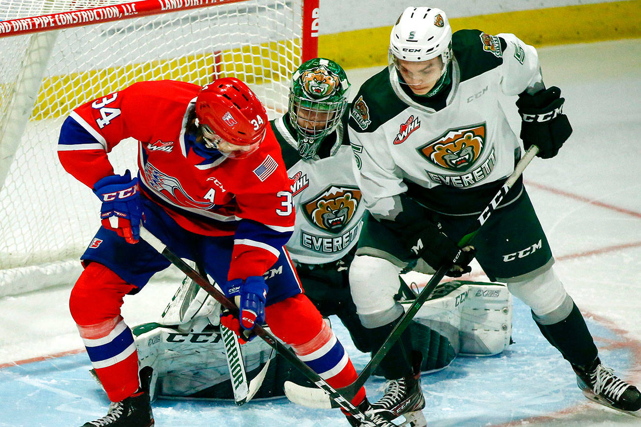Chiefs' Adam Beckman (left) and Silvertips' Zach Ashton struggle for the puck in front of Silvertips' Dustin Wolf during the final home game Friday night at Angel of the Winds Arena in Everett on May 7, 2021.  (Kevin Clark / The Herald)