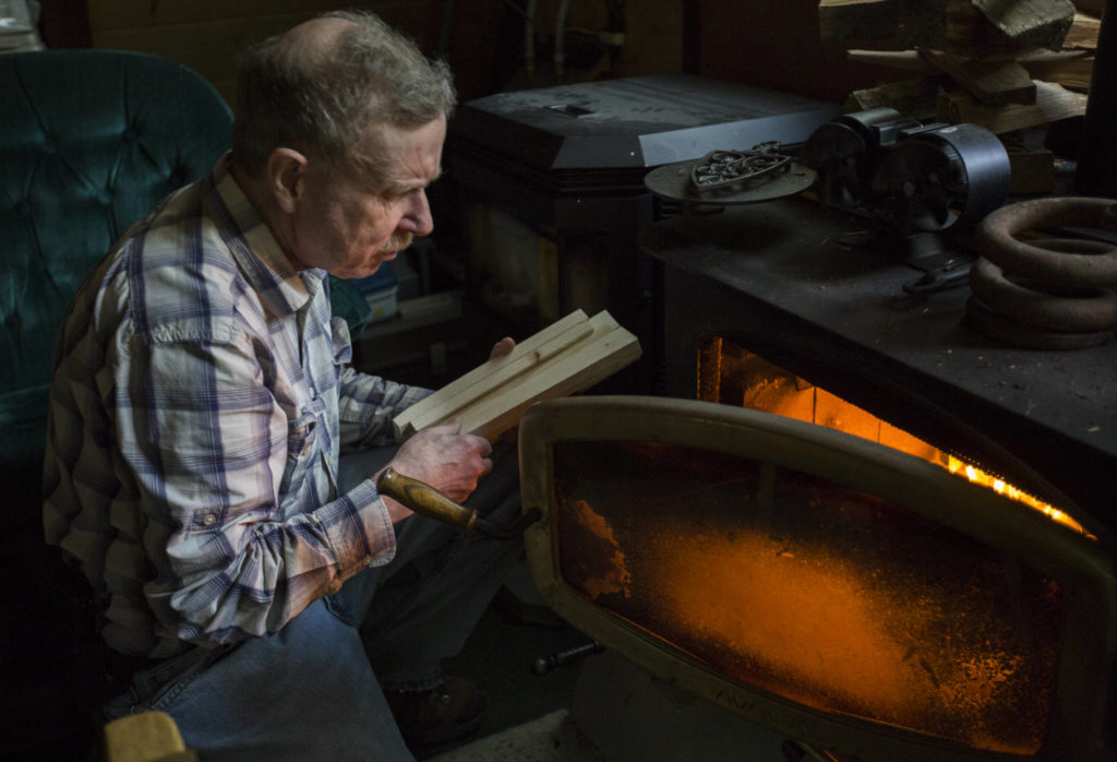 Bruce Kimball adds wood to the fire in his cabin on May 9 in Index. (Olivia Vanni / The Herald)
