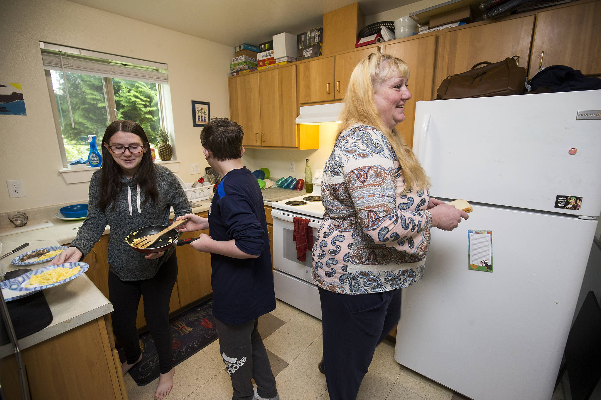 Heather Adams, a single mother of three, teaches her children Kiara and Matthew how to make breakfast in their apartment in Arlington. (Andy Bronson / The Herald)