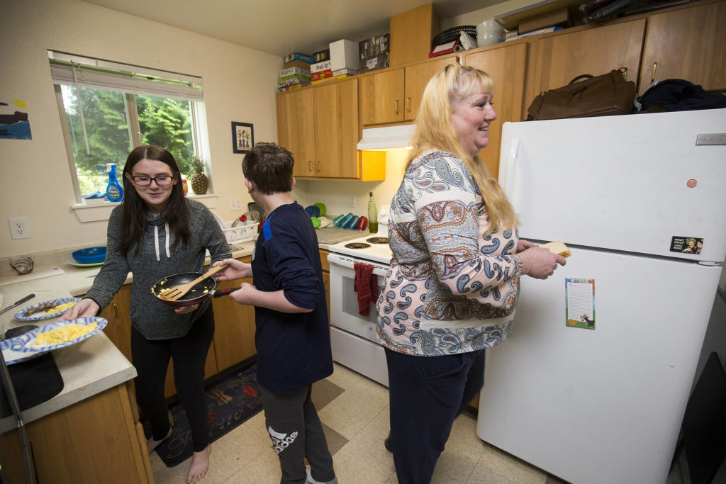 Heather Adams, a single mother of three, teaches her children Kiara and Matthew how to make breakfast in their apartment in Arlington. (Andy Bronson / The Herald)

