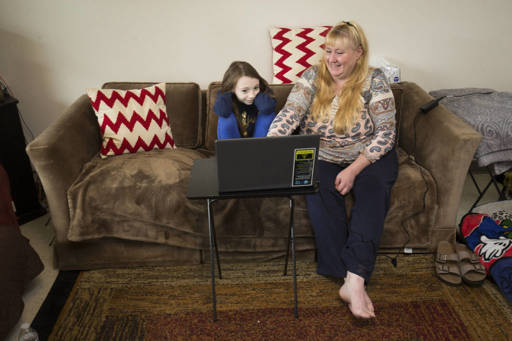 Heather Adams reads with her youngest daughter, Phoenix, at their apartment in Arlington. (Andy Bronson / The Herald) 
