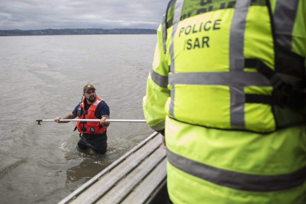 Beau Jess walks on a sandbar as people get out of the boat to start their search for Charlie Cortez on May 28 in Possession Sound. (Olivia Vanni / The Herald)
