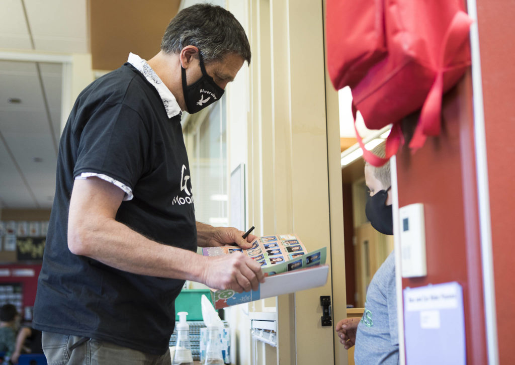 Jeff Thoreson signs a student yearbook on his last in-person day of school on Thursday in Snohomish. (Olivia Vanni / The Herald) 
