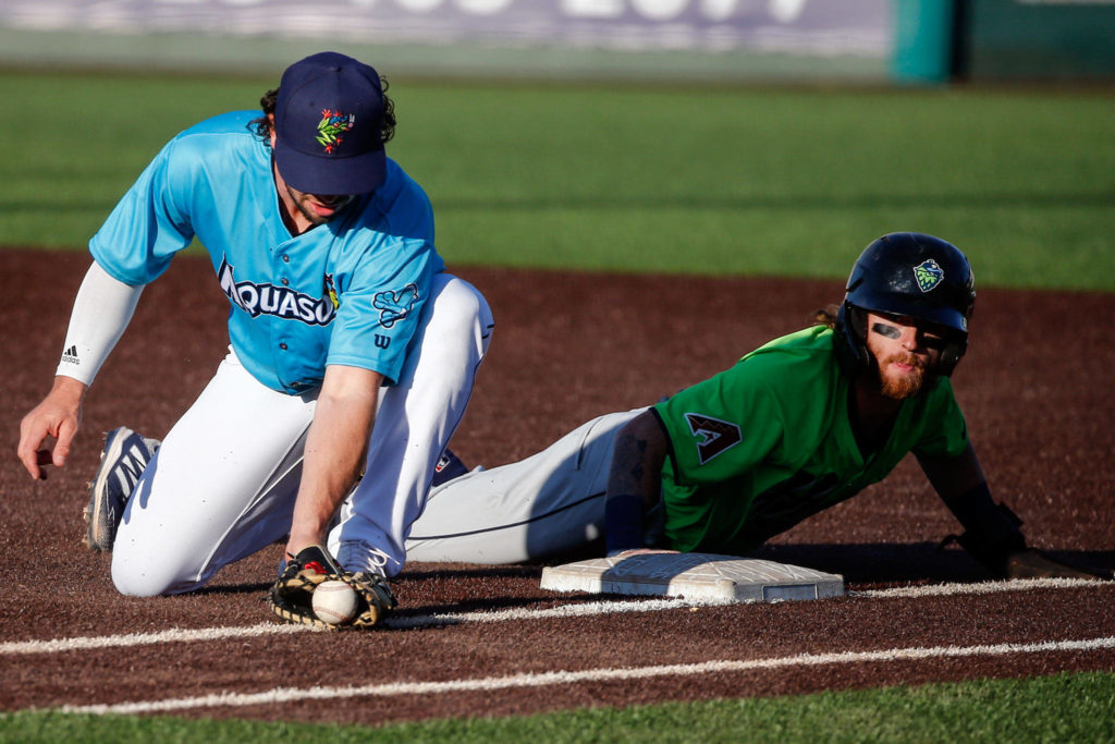 The AquaSox’s Connor Hoover attempts a tag on the Hops’ Cam Coursey during a game on Thursday evening at Funko Field in Everett. (Kevin Clark / The Herald)
