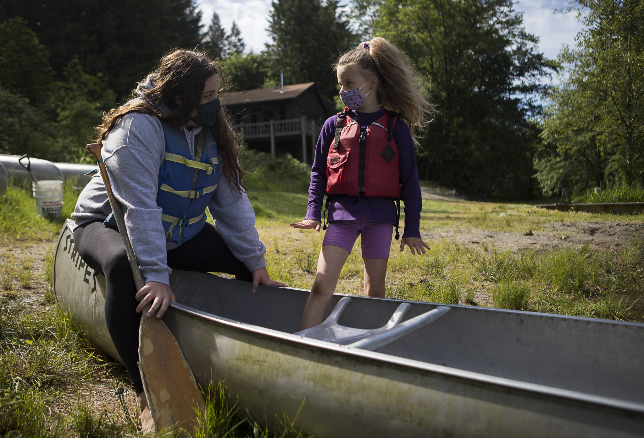 Hannah Davis talks about the importance of a three-point stance in a canoe with camper Zienna Zink, 8, before heading out on Crabapple Lake. (Olivia Vanni / The Herald)