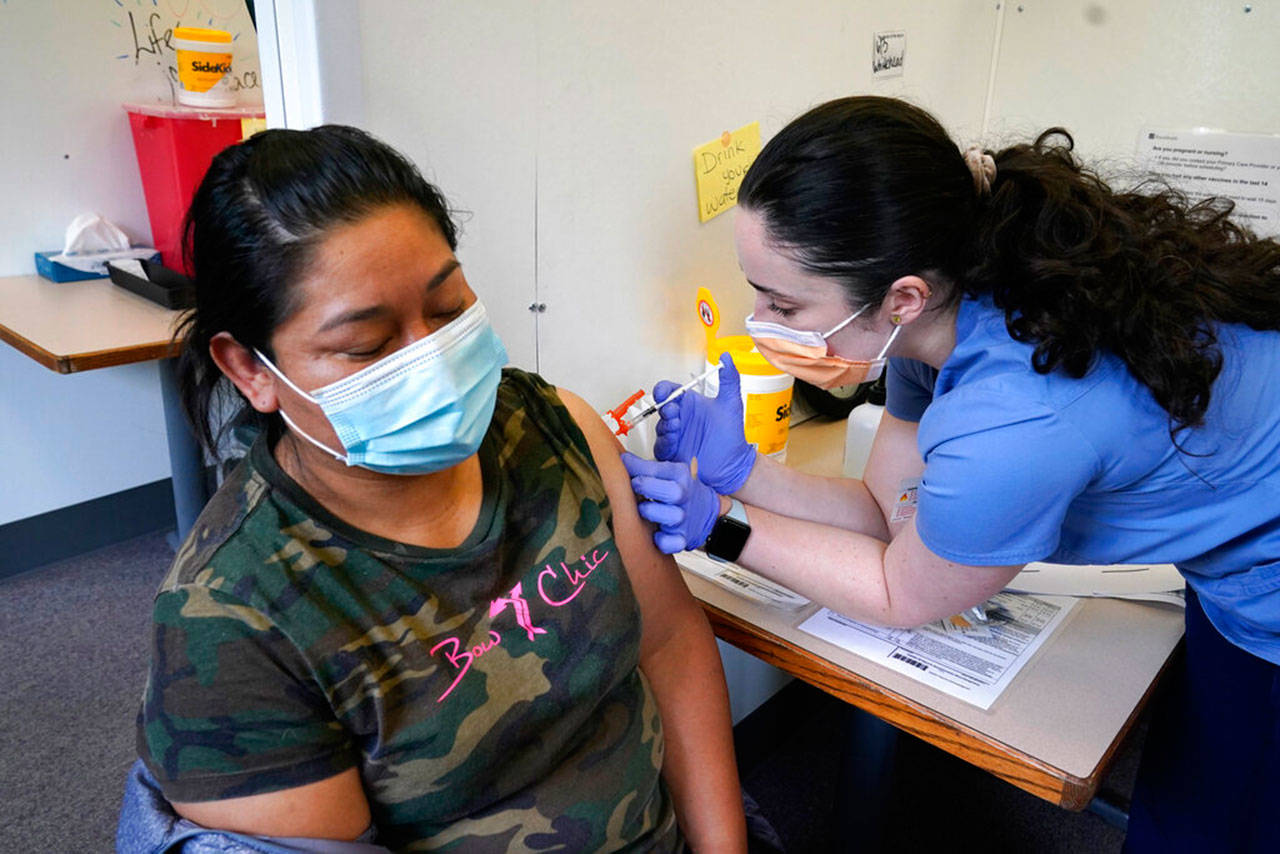 Medical assistant Andreea Marian (right) gives a covid-19 vaccine to Gabina Morales at a clinic at PeaceHealth St. Joseph Medical Center on June 3, in Bellingham. Washington is the latest state to offer prizes to encourage people to get vaccinated against covid-19, with Gov. Jay Inslee last week announcing a series of giveaways during the month of June that includes lottery drawings totaling $2 million, college tuition assistance, airline tickets and game systems. (Elaine Thompson / Associated Press)