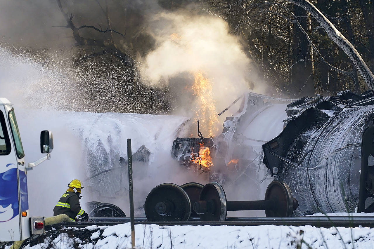 A firefighter sprays foam on burning, derailed train cars Dec. 22, 2020, in Custer, Washington. (AP Photo/Elaine Thompson, file)