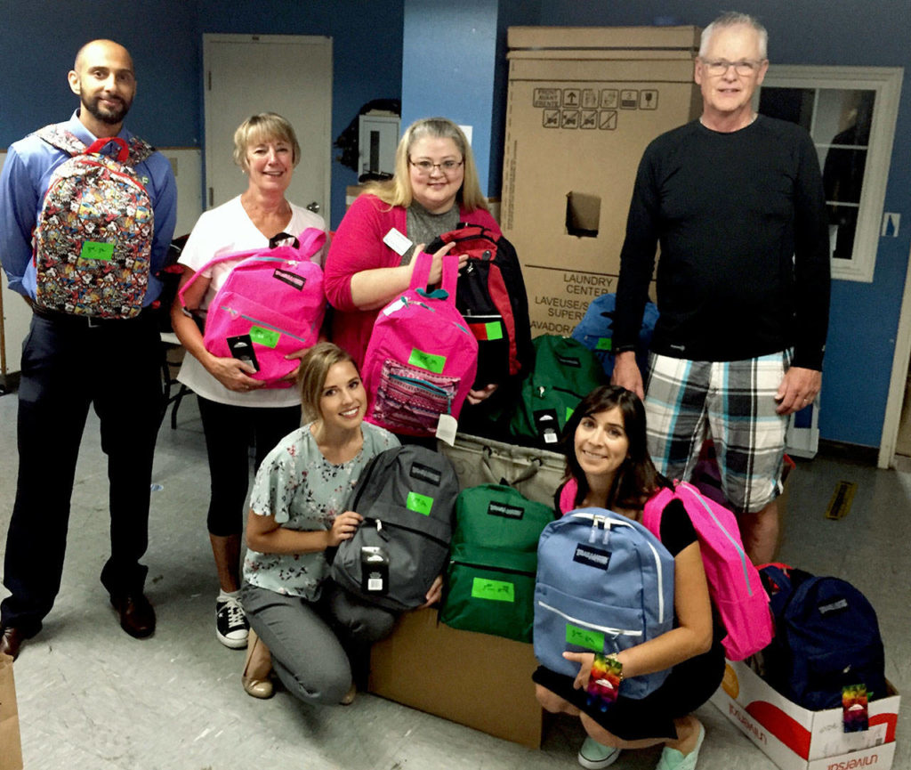 Katie Thurston, left in front row, was among volunteers from First Financial Northwest Bank and the Edmonds Young Professionals packing 135 backpacks with school supplies for the YWCA School Days program in 2018. Front row at right is Yvonne De La Rosa. Back row, from left: Yusuf Hansia, Jane Tocco, Kristie Gilchrist and Gary Walderman. (Herald file photo)
