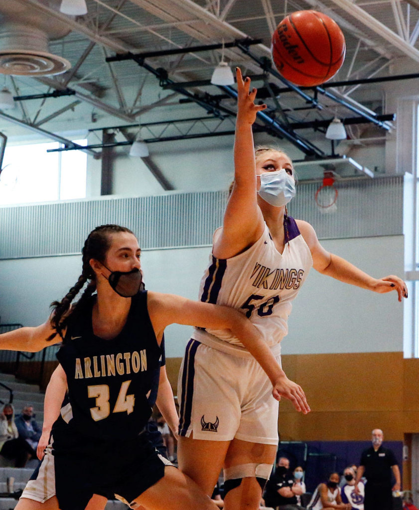 Lake Stevens’ Bella Evans (right) reaches for a loose ball with Arlington’s Jenna Villa defending during a game on Wednesday evening at Lake Stevens High School. Arlington won 80-71. (Kevin Clark / The Herald)
