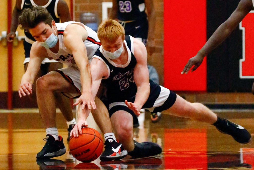 Mountlake Terrace’s Trazz Pepper (left) and Kamiak’s Nolan Martin dive for a loose ball during a game Thursday evening at Mountlake Terrace High School. The Hawks won 65-59. (Kevin Clark / The Herald)
