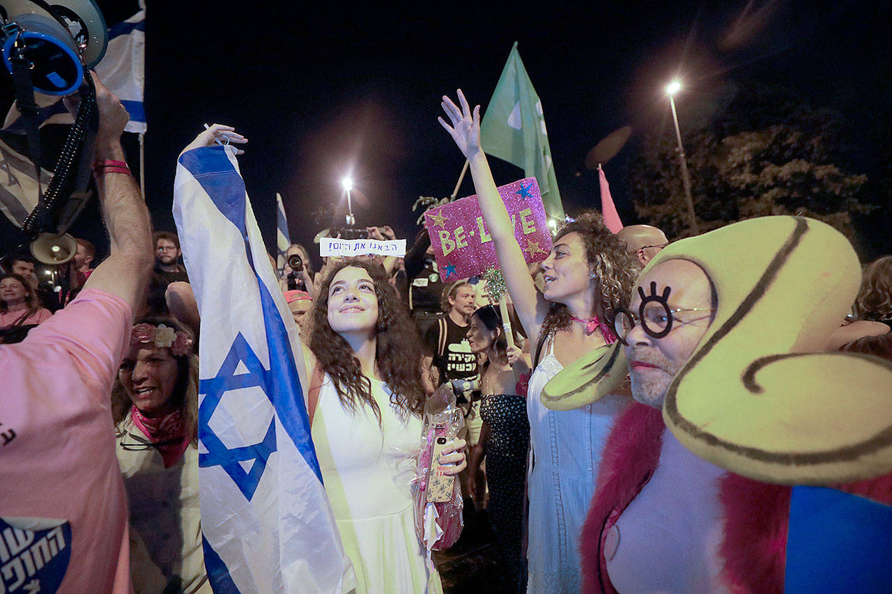 Israelis celebrate the swearing in of the new government in Jerusalem on Sunday. Israel’s parliament has voted in favor of a new coalition government, formally ending Prime Minister Benjamin Netanyahu’s historic 12-year rule. (AP Photo/Sebastian Scheiner)